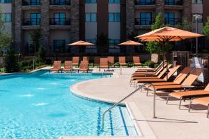 a swimming pool with lounge chairs and umbrellas at Courtyard by Marriott Fort Worth Alliance Town Center in Fort Worth