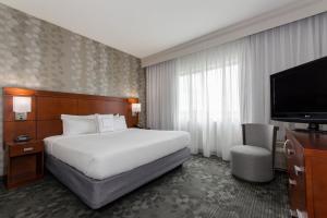 a hotel room with a bed and a flat screen tv at Courtyard Charlotte Concord in Concord