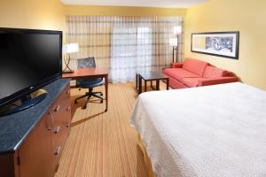 a hotel room with a bed and a flat screen tv at Courtyard by Marriott Dallas Plano in Legacy Park in Plano