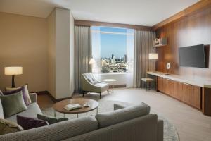 Marriott Executive Apartments Kuwait City في الكويت: غرفة معيشة مع أريكة وتلفزيون