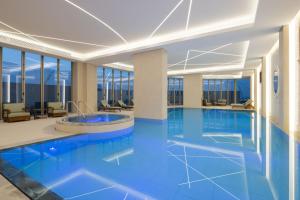 Marriott Executive Apartments Kuwait City في الكويت: مسبح في فندق بالادوار الزرقاء والنوافذ