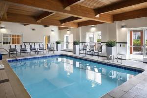 a swimming pool with chairs and tables in a building at Fairfield Inn & Suites Denver Airport in Denver
