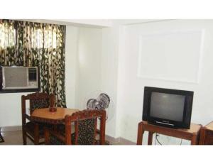 a living room with a tv and a table and chairs at Hotel Swagat, Jammu in Jammu