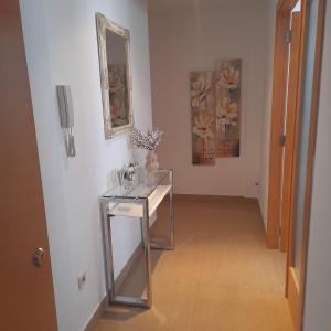 a hallway with a glass table and paintings on the wall at Apartamento San Vicente in Villar del Arzobispo