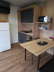 een keuken met een houten tafel en een witte koelkast bij Mobilna hiška 21 v kampu BIG BERRY in Metlika