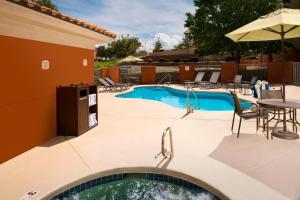 a swimming pool with a table and chairs and an umbrella at Fairfield Inn & Suites by Marriott Albuquerque Airport in Albuquerque
