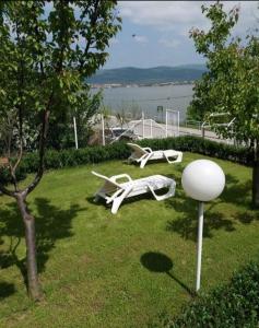two white lawn chairs sitting on the grass at Apartman Sunce in Golubac