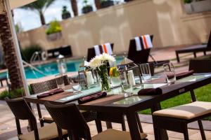 una mesa con vasos y flores junto a una piscina en Renaissance Baton Rouge Hotel en Baton Rouge