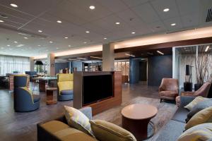 a lobby with a large screen tv and chairs at Courtyard by Marriott Atlanta Alpharetta/Avalon Area in Alpharetta