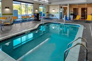 a large swimming pool with blue water in a building at Fairfield Inn & Suites by Marriott Lansing at Eastwood in Lansing