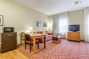 a hotel room with a table and a couch and a television at TownePlace Suites by Marriott Dallas Bedford in Bedford