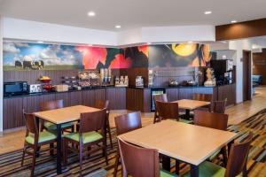 a restaurant with tables and chairs and a kitchen at Fairfield Inn & Suites by Marriott Denver Aurora/Medical Center in Aurora