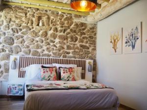 uma cama num quarto com uma parede de pedra em La Casa Rebonita ACCESA em Candelario