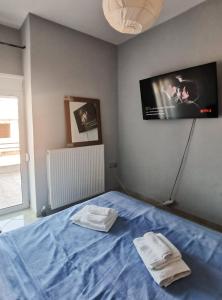 a bedroom with a blue bed with a tv on the wall at Summer blossom apartment in Chalkida