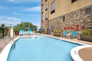 einen Pool mit Stühlen und ein Gebäude in der Unterkunft TownePlace Suites by Marriott Nashville Smyrna in Smyrna