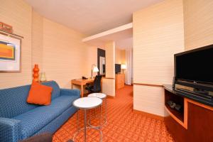 a hotel room with a blue couch and a flat screen tv at Fairfield Inn & Suites White Marsh in Baltimore