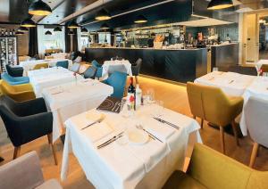 een restaurant met witte tafels en stoelen en een bar bij Tailormade Hotel RIGIBLICK Küssnacht in Küssnacht