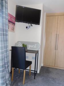 a desk with a chair and a television on a wall at Double room with ensuite, tea & coffee, Falkirk, Scotland in Falkirk