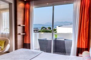 a bedroom with a balcony with a view of the ocean at AC Hotel by Marriott Ambassadeur Antibes - Juan Les Pins in Juan-les-Pins
