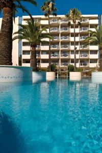 een zwembad tegenover een hotel met palmbomen bij AC Hotel by Marriott Ambassadeur Antibes - Juan Les Pins in Juan-les-Pins