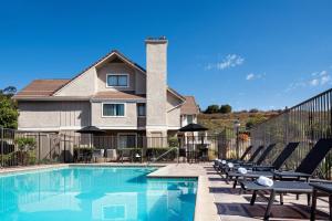 a swimming pool with lounge chairs and a house at Residence Inn San Diego La Jolla in San Diego