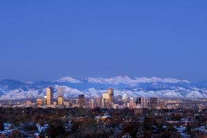 a city skyline with snow covered mountains in the background at Renaissance Denver Central Park Hotel in Denver