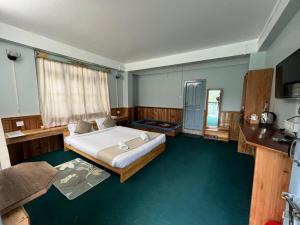a bedroom with a large bed in a room with green carpet at Mount Khang Hotel in Lachen