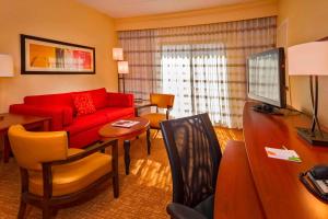 a living room with a red couch and a table at Courtyard Virginia Beach Norfolk in Virginia Beach