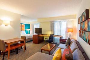 ルイスビルにあるResidence Inn Louisville Northeastのソファとベッドルームが備わるホテルルームです。