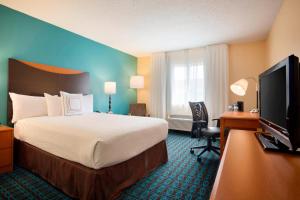 a hotel room with a bed and a flat screen tv at Fairfield Inn & Suites by Marriott Dallas Plano in Plano