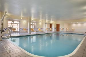 a pool in a hotel with yellow chairs and tables at Fairfield Inn & Suites by Marriott Dallas Plano in Plano
