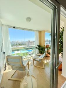 Bright apartment with terrace, pool and beach في توريمولينوس: غرفة معيشة مع كرسيين ونافذة كبيرة