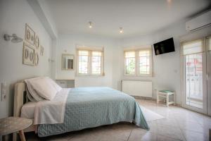 - une chambre blanche avec un lit et une télévision dans l'établissement Meteora Sky House, à Kalambaka