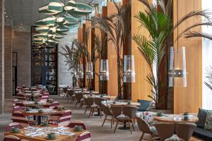 un restaurante con mesas, sillas y palmeras en Barranquilla Marriott Hotel, en Barranquilla