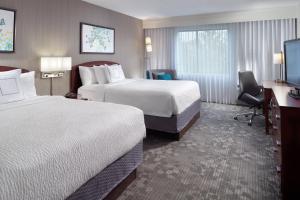 a hotel room with two beds and a desk at Courtyard by Marriott Atlanta Alpharetta in Alpharetta