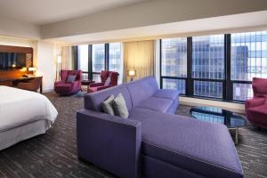 una camera d'albergo con un divano viola e un letto di Sheraton Grand Los Angeles a Los Angeles