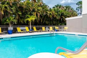 a swimming pool with chairs and palm trees at Fairfield Inn & Suites by Marriott Fort Myers Cape Coral in Fort Myers