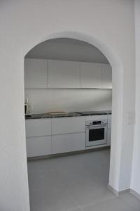 a kitchen with white cabinets and an archway at Villa Perla Nou in Binibeca