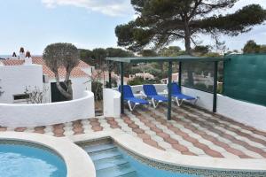 a patio with blue chairs and a swimming pool at Villa Perla Nou in Binibeca