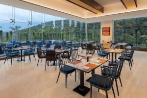 a restaurant with tables and chairs and large windows at Fairfield by Marriott Dehradun in Dehradun