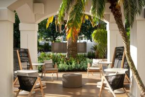 a patio with chairs and tables and palm trees at Palm Beach Gardens Marriott in Palm Beach Gardens