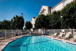 une grande piscine avec des chaises et un bâtiment dans l'établissement TownePlace Suites by Marriott Texarkana, à Texarkana - Texas