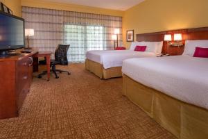 a hotel room with two beds and a desk and a television at Courtyard by Marriott Richmond West in Richmond