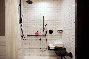 a white tiled bathroom with a shower and a bench at Moxy Richmond Downtown in Richmond