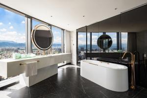 ein Badezimmer mit einer großen weißen Badewanne und Spiegeln in der Unterkunft Le Méridien Taichung in Taichung