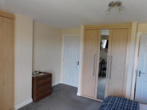 a bedroom with a bed and a dresser and a mirror at Double room with ensuite, tea & coffee, Falkirk, Scotland in Falkirk