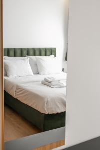 - un lit avec une tête de lit verte et des oreillers blancs dans l'établissement Sun Marco Apartments in Athens, à Athènes