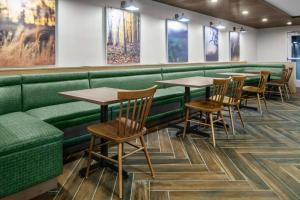 ロッキーマウントにあるFairfield Inn & Suites Rocky Mountの緑のブース、木製のテーブルと椅子が備わるレストラン
