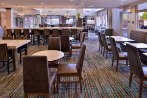 a restaurant with tables and chairs and a bar at Residence Inn by Marriott East Lansing in East Lansing