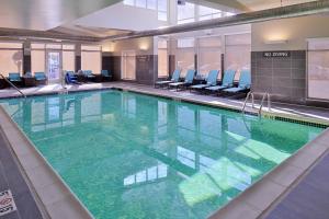a large swimming pool with green water in a building at Residence Inn by Marriott East Lansing in East Lansing